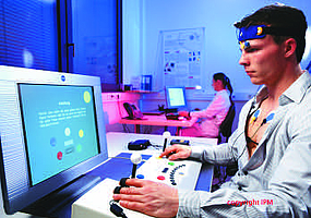 Junger Mann mit Sensoren an Kopf und Brust löst Aufgaben am Computer